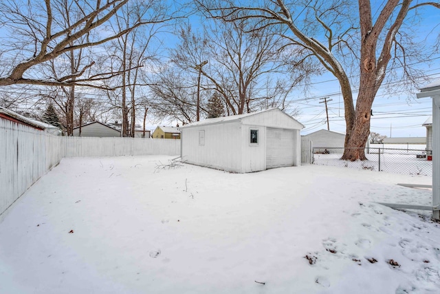 yard layered in snow featuring an outbuilding and a garage