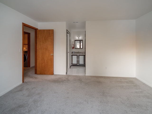 spare room with washer / dryer and light carpet