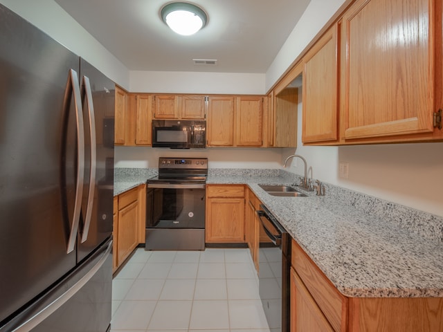 kitchen featuring light stone countertops, light tile patterned floors, sink, and black appliances