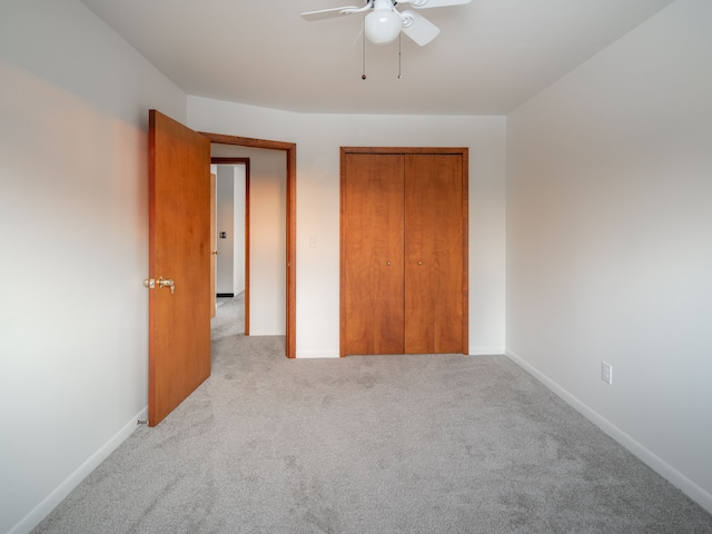 unfurnished bedroom featuring ceiling fan, light colored carpet, and a closet