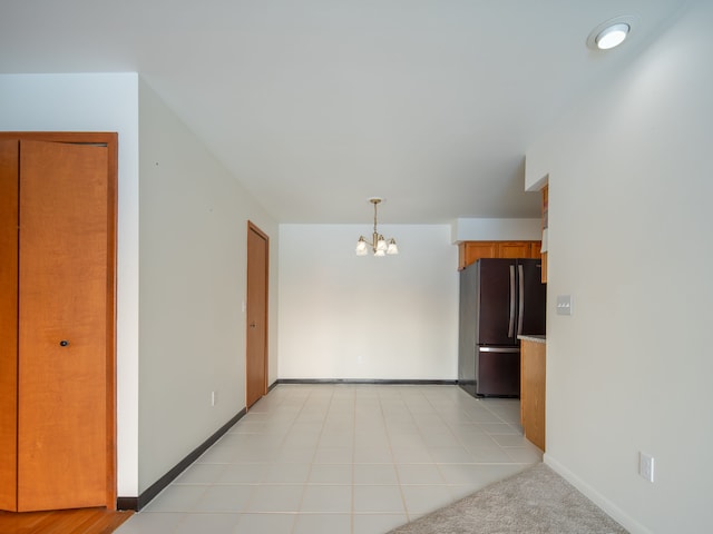 interior space with hanging light fixtures, light tile patterned floors, black fridge, and an inviting chandelier