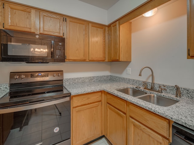 kitchen featuring black appliances, light stone countertops, and sink