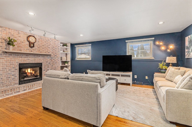 living room featuring rail lighting, light hardwood / wood-style floors, and a fireplace