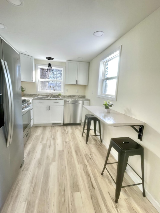 kitchen with light hardwood / wood-style floors, plenty of natural light, white cabinets, and stainless steel appliances