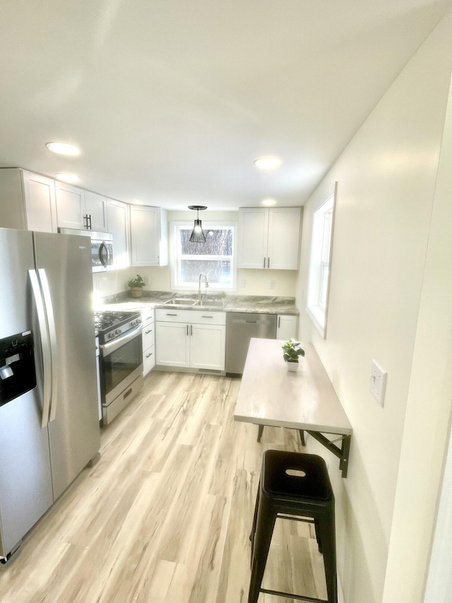 kitchen with light wood-type flooring, stainless steel appliances, white cabinetry, and sink