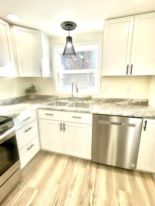 kitchen featuring white cabinetry, appliances with stainless steel finishes, pendant lighting, light hardwood / wood-style flooring, and sink