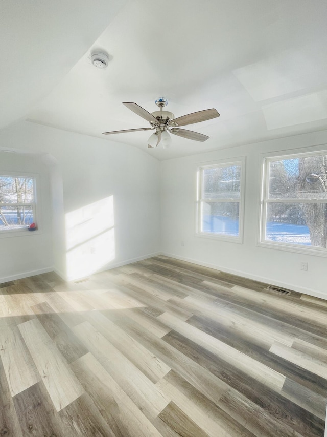 empty room with light wood-type flooring, ceiling fan, and a healthy amount of sunlight