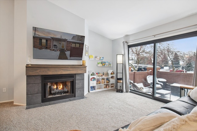 carpeted living room with a tiled fireplace and vaulted ceiling