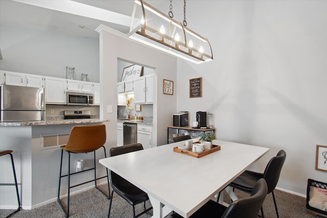 dining area featuring light colored carpet, a notable chandelier, and sink