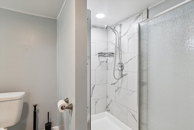 bathroom with tiled shower, crown molding, and toilet