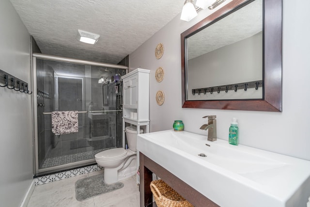 bathroom featuring toilet, vanity, tile patterned flooring, a textured ceiling, and a shower with door