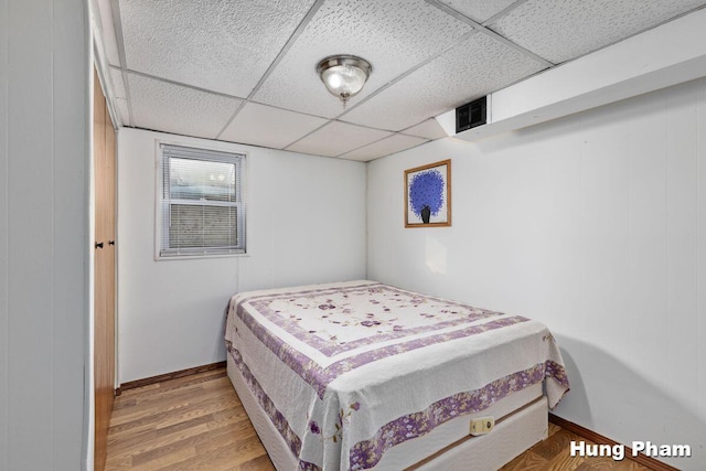 bedroom featuring a drop ceiling and hardwood / wood-style floors