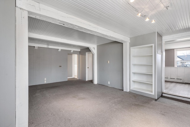 carpeted empty room with a baseboard radiator and built in shelves