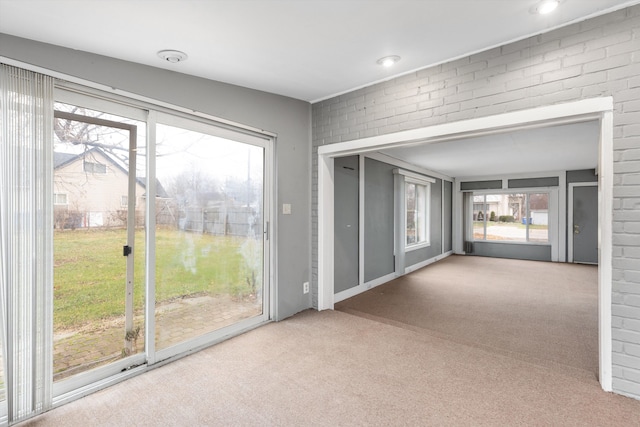 carpeted empty room with brick wall