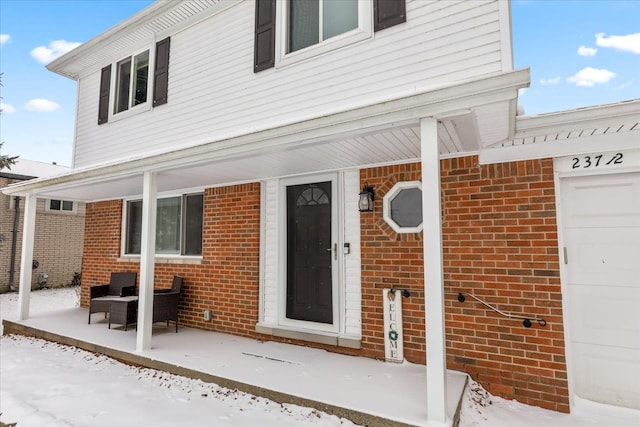 snow covered property entrance featuring a garage