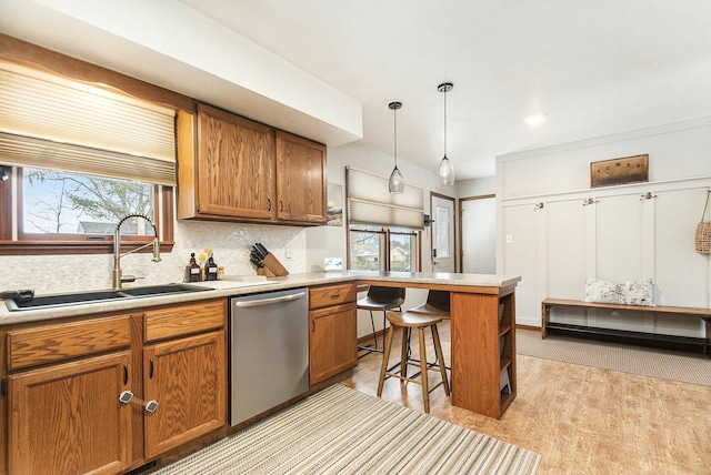 kitchen featuring dishwasher, pendant lighting, sink, light wood-type flooring, and a breakfast bar area