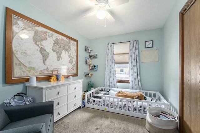 bedroom featuring ceiling fan, light carpet, and a crib