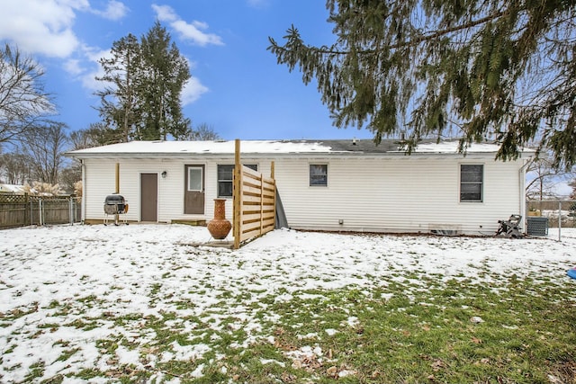 snow covered back of property featuring central AC unit