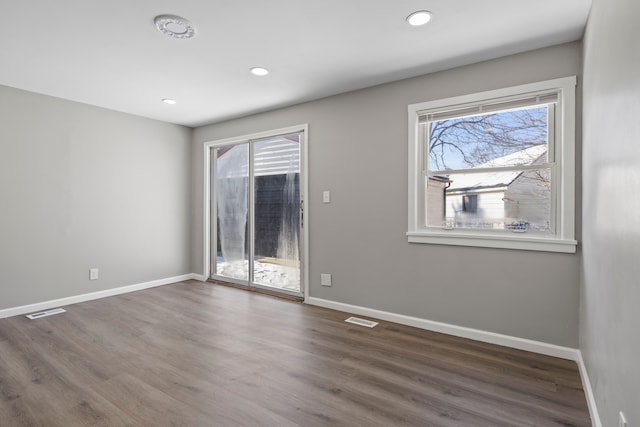 spare room featuring a healthy amount of sunlight and dark hardwood / wood-style floors