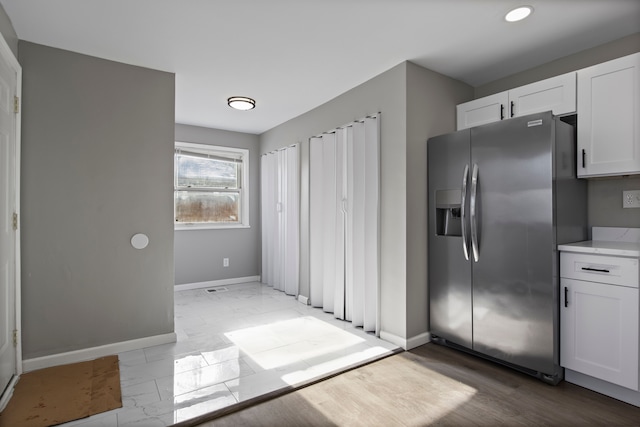 kitchen with stainless steel fridge and white cabinetry