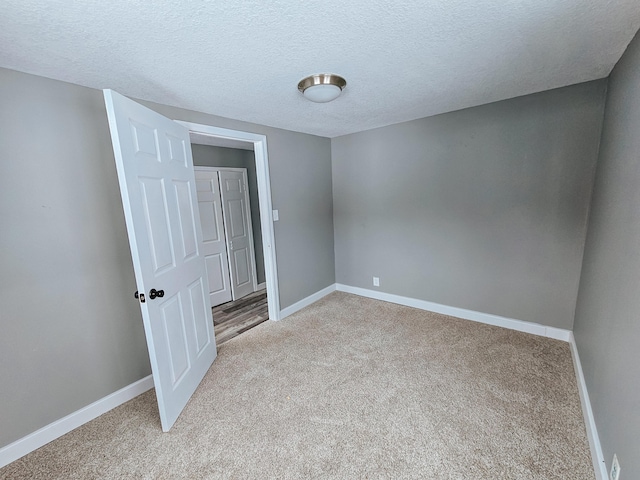 unfurnished bedroom with light colored carpet, baseboards, and a textured ceiling