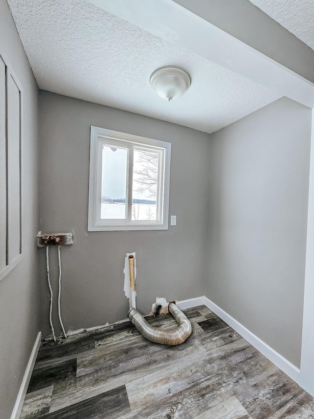 laundry room with wood finished floors, a textured ceiling, and baseboards