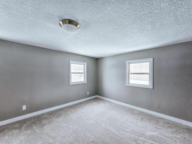 empty room with baseboards, carpet, and a textured ceiling