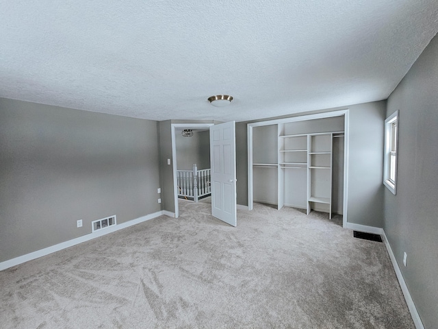 unfurnished bedroom featuring a textured ceiling, carpet flooring, baseboards, and a closet