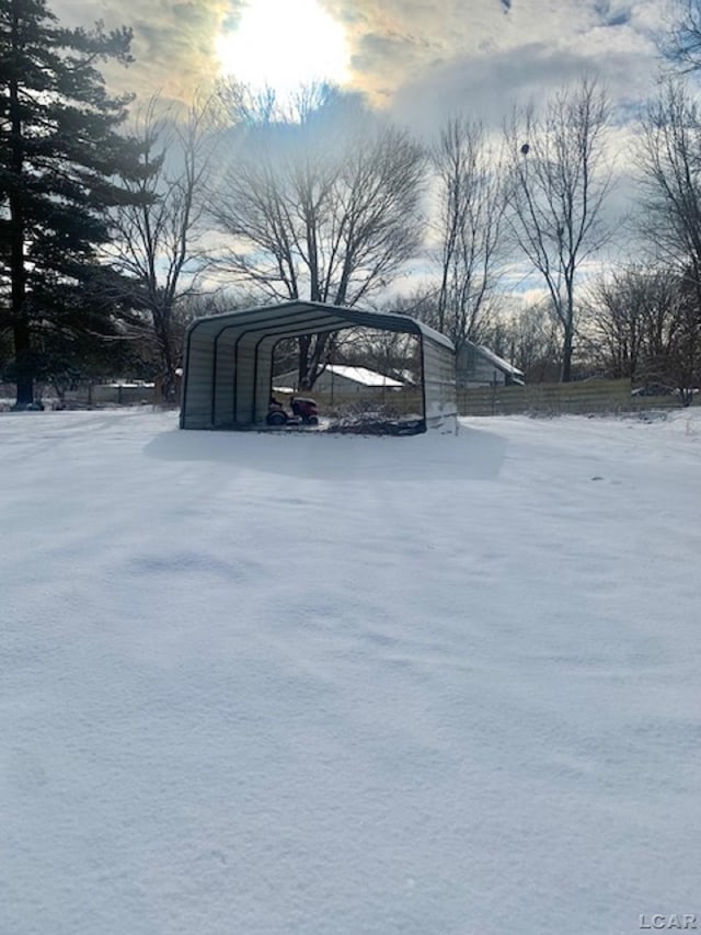 yard layered in snow featuring a carport