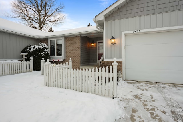 snow covered property entrance featuring a garage