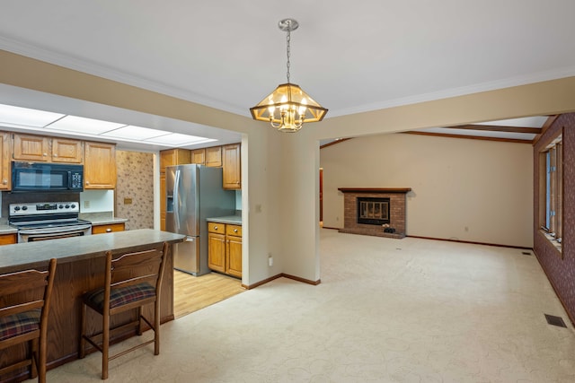 kitchen featuring appliances with stainless steel finishes, a breakfast bar, pendant lighting, ornamental molding, and a brick fireplace