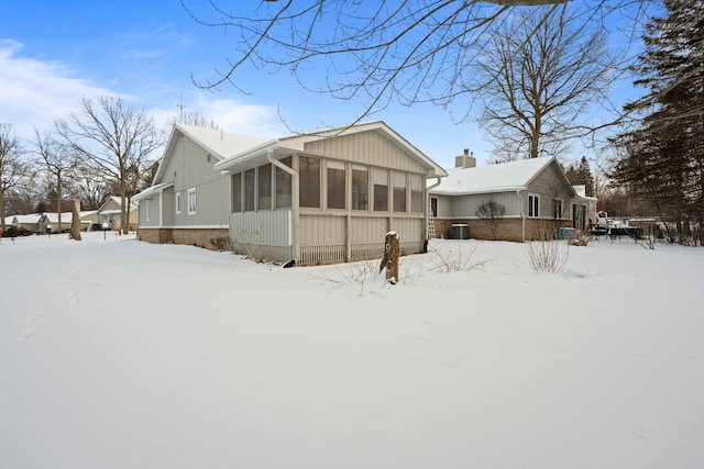 snow covered property featuring a sunroom