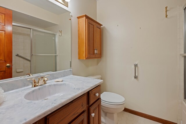 bathroom with vanity, toilet, and a shower with door