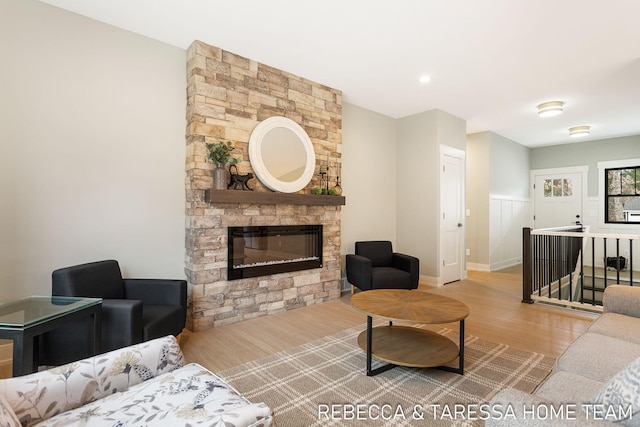 living room featuring a stone fireplace and light hardwood / wood-style flooring