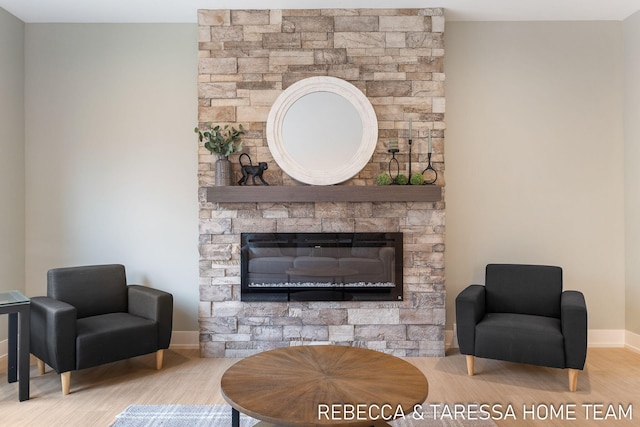 living area featuring a stone fireplace and light hardwood / wood-style floors