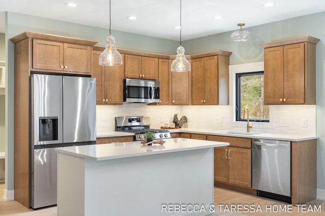 kitchen with stainless steel appliances, a kitchen island, sink, and pendant lighting