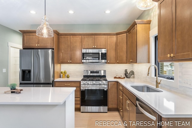 kitchen with sink, backsplash, hanging light fixtures, stainless steel appliances, and light hardwood / wood-style floors