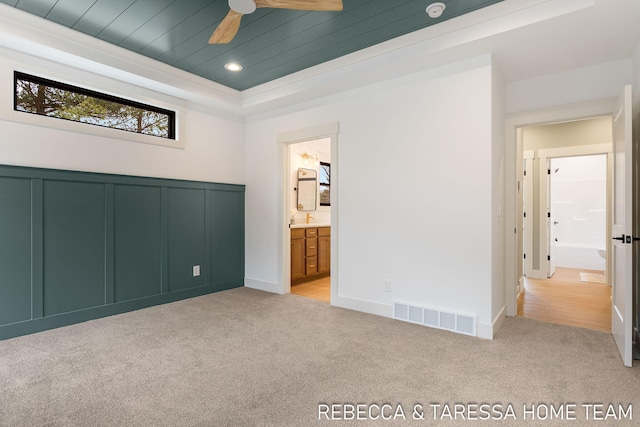 unfurnished bedroom with light colored carpet, a tray ceiling, ensuite bath, and wooden ceiling