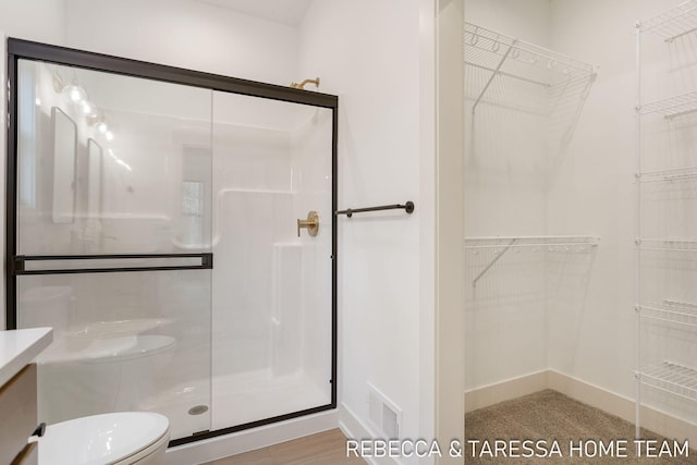 bathroom with a shower with door, vanity, and toilet