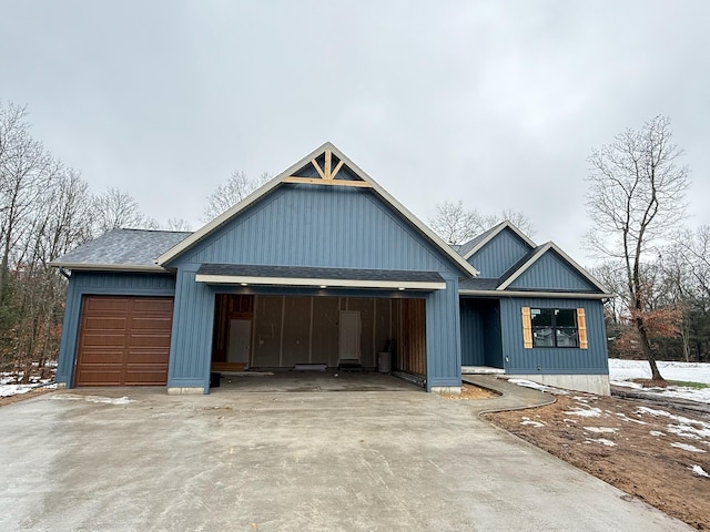 view of front of property with an attached garage, concrete driveway, and roof with shingles