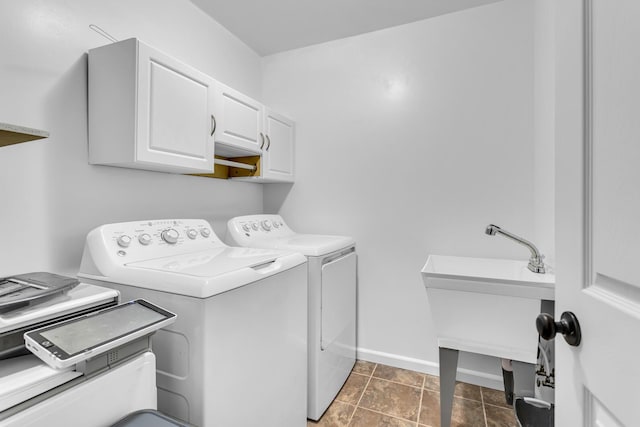 laundry room featuring dark tile patterned floors, sink, washing machine and clothes dryer, and cabinets