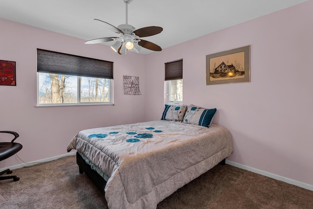 bedroom featuring ceiling fan, dark carpet, and multiple windows