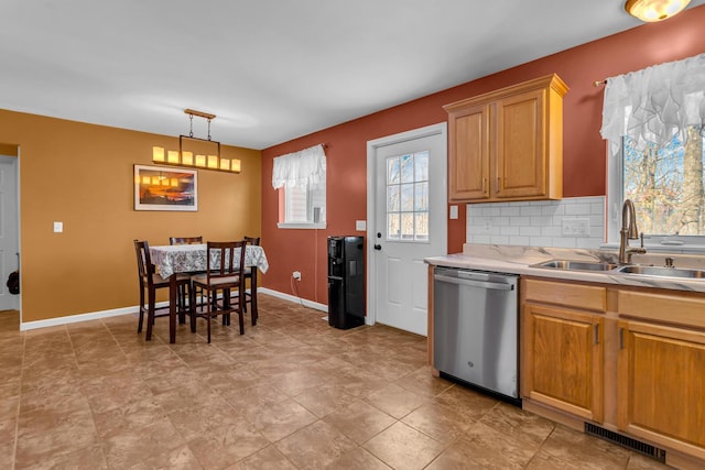 kitchen featuring stainless steel dishwasher, decorative light fixtures, sink, and tasteful backsplash