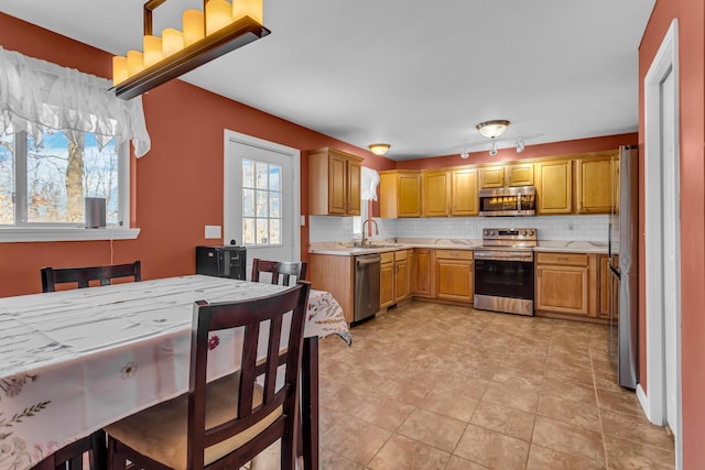 kitchen with backsplash, appliances with stainless steel finishes, and sink