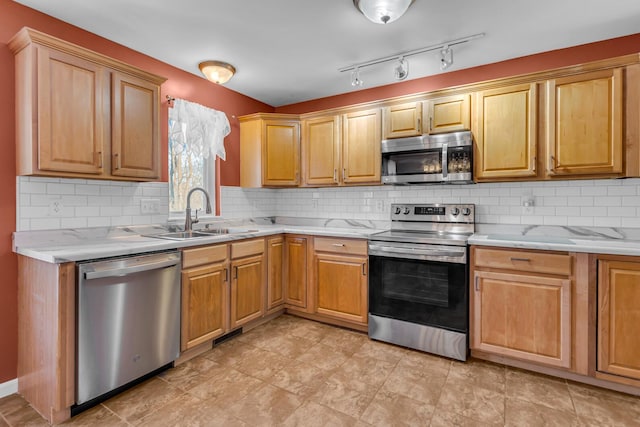 kitchen featuring decorative backsplash, sink, light stone counters, and appliances with stainless steel finishes