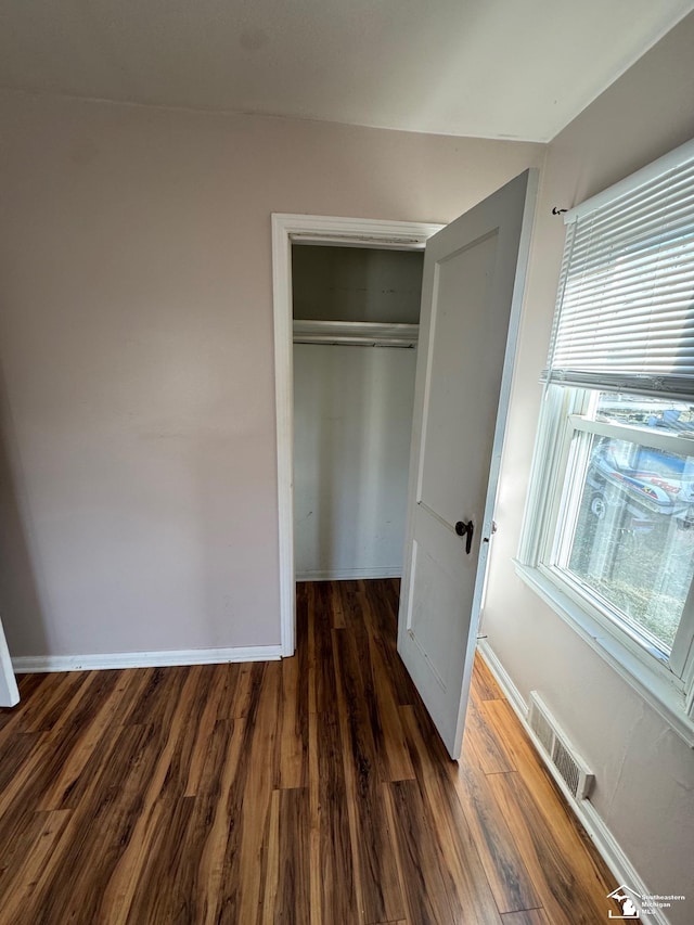 unfurnished bedroom with a closet and dark hardwood / wood-style floors