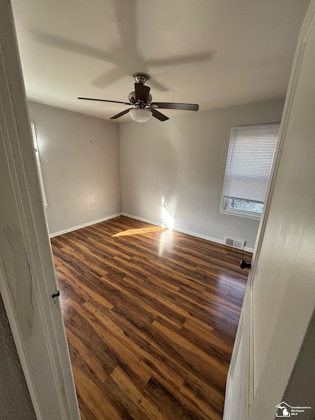 empty room with ceiling fan and dark hardwood / wood-style floors