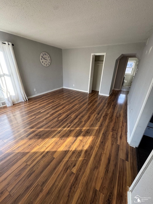 interior space with a textured ceiling and dark hardwood / wood-style floors