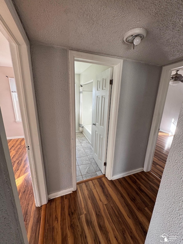 corridor with a textured ceiling and hardwood / wood-style floors