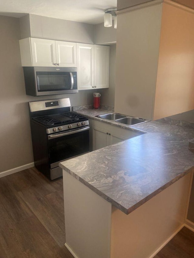 kitchen featuring stainless steel appliances, white cabinets, dark hardwood / wood-style flooring, and kitchen peninsula